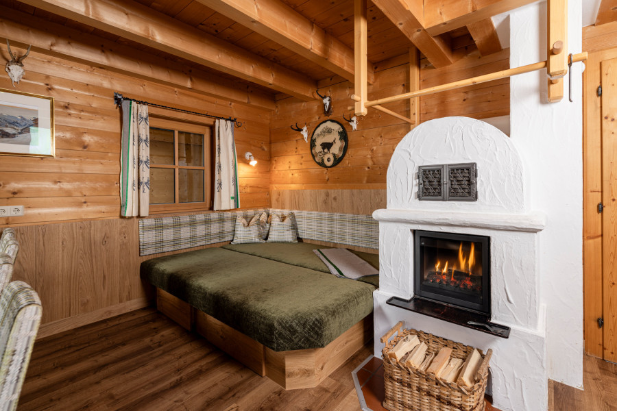 Wohnbereich im Erdgeschoss der Family Lodge Maximilian mit gemütlichem Holzofen und Sitzmöglichkeiten.