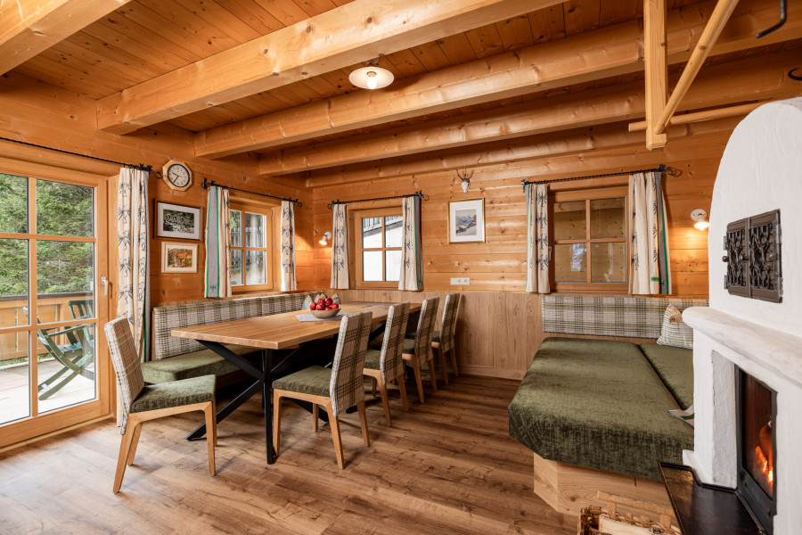 Offener Wohnbereich der Family Lodge Maximilian mit großem Esstisch und Sofaecke.