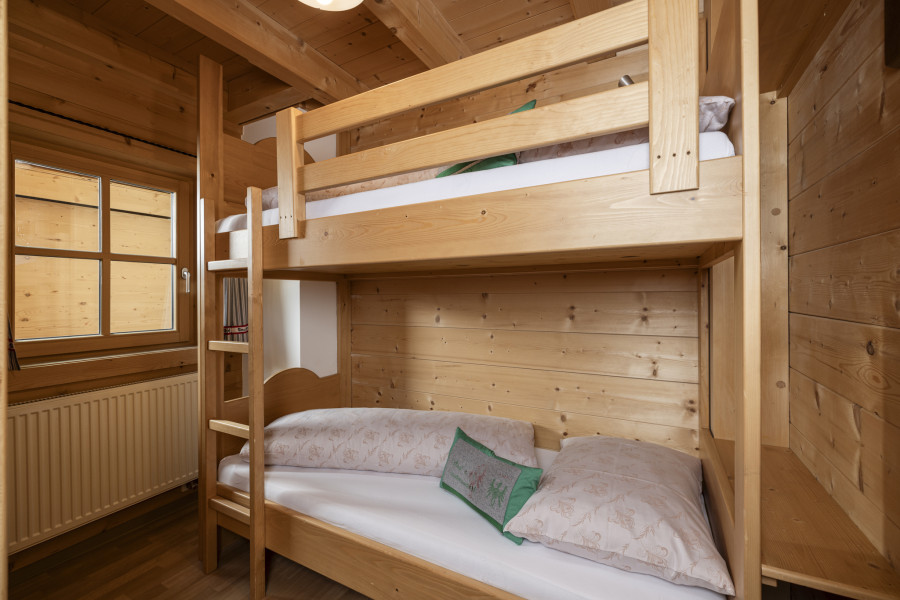 Schlafzimmer im Erdgeschoss der Family Lodge Maximilian mit Stockbett aus Holz.