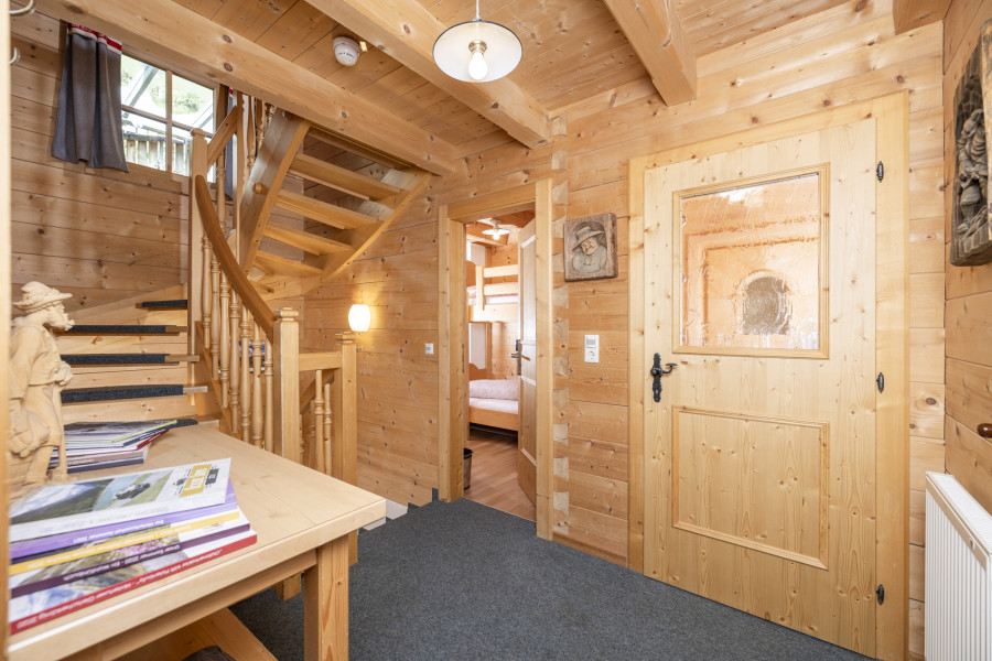 Korridor im Erdgeschoss der Family Lodge Maximilian mit Holzwänden und Zugang zu den Zimmern.