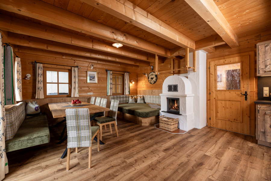 Family Lodge Maximilian, Wohnbereich mit Esstisch, Couch und Holzofen