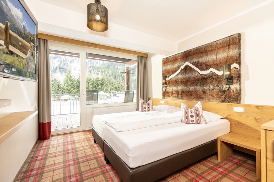 Schlafzimmer der Juniorsuite Hintertux mit Zugang zum Balkon und Bergblick.