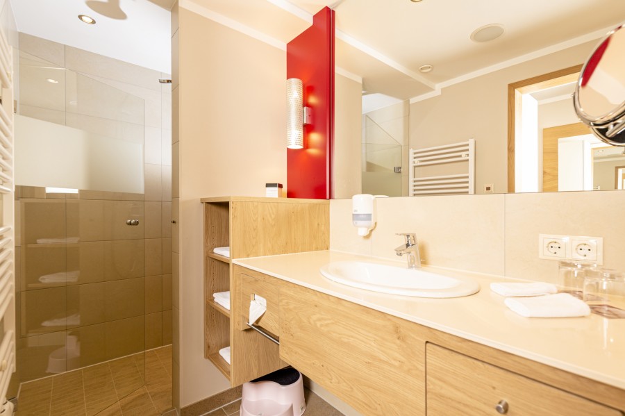 Offenes Badezimmer der Juniorsuite Hintertux mit eleganter Ausstattung und Holzdetails.