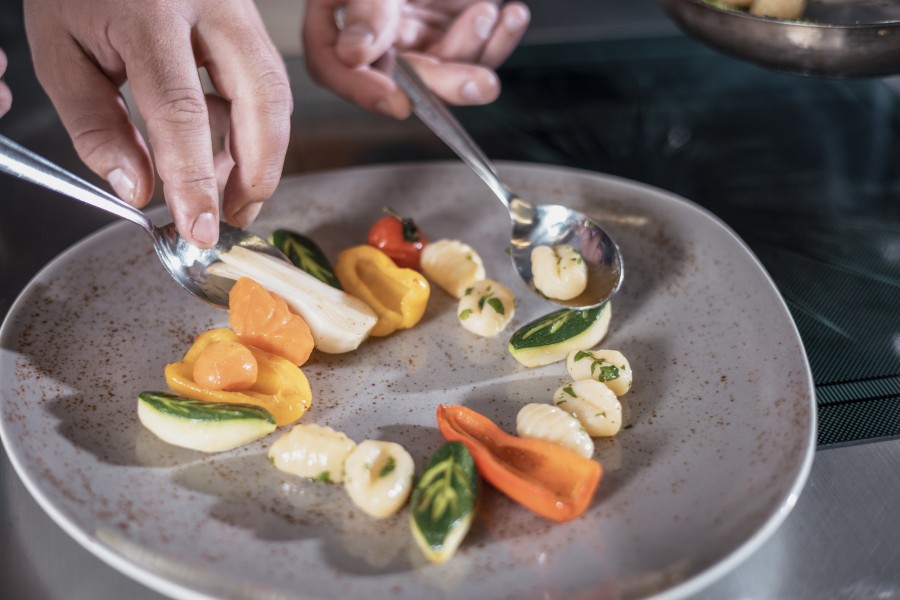 Nahaufnahme eines Gerichts mit frisch zubereitetem Gemüse, das in der Küche angerichtet wird.